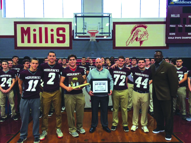 Patriots and Pro Football Hall of Fame linebacker Andre Tippett presented the Mohawks football program with a $2,000 donation on behalf of the New England Patriots Charitable Foundation on December 6, in honor of Coach Dana Olson, who was named New England Patriots High School Coach of the Year. Olson and Tippett are shown with the team captains and teammates in the background.