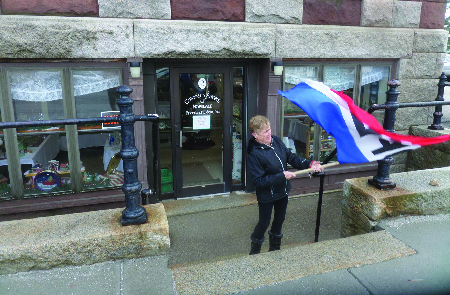 Volunteer Rosemary Trevani unfurls the “Open” flag as the Curiosity opens its doors for business