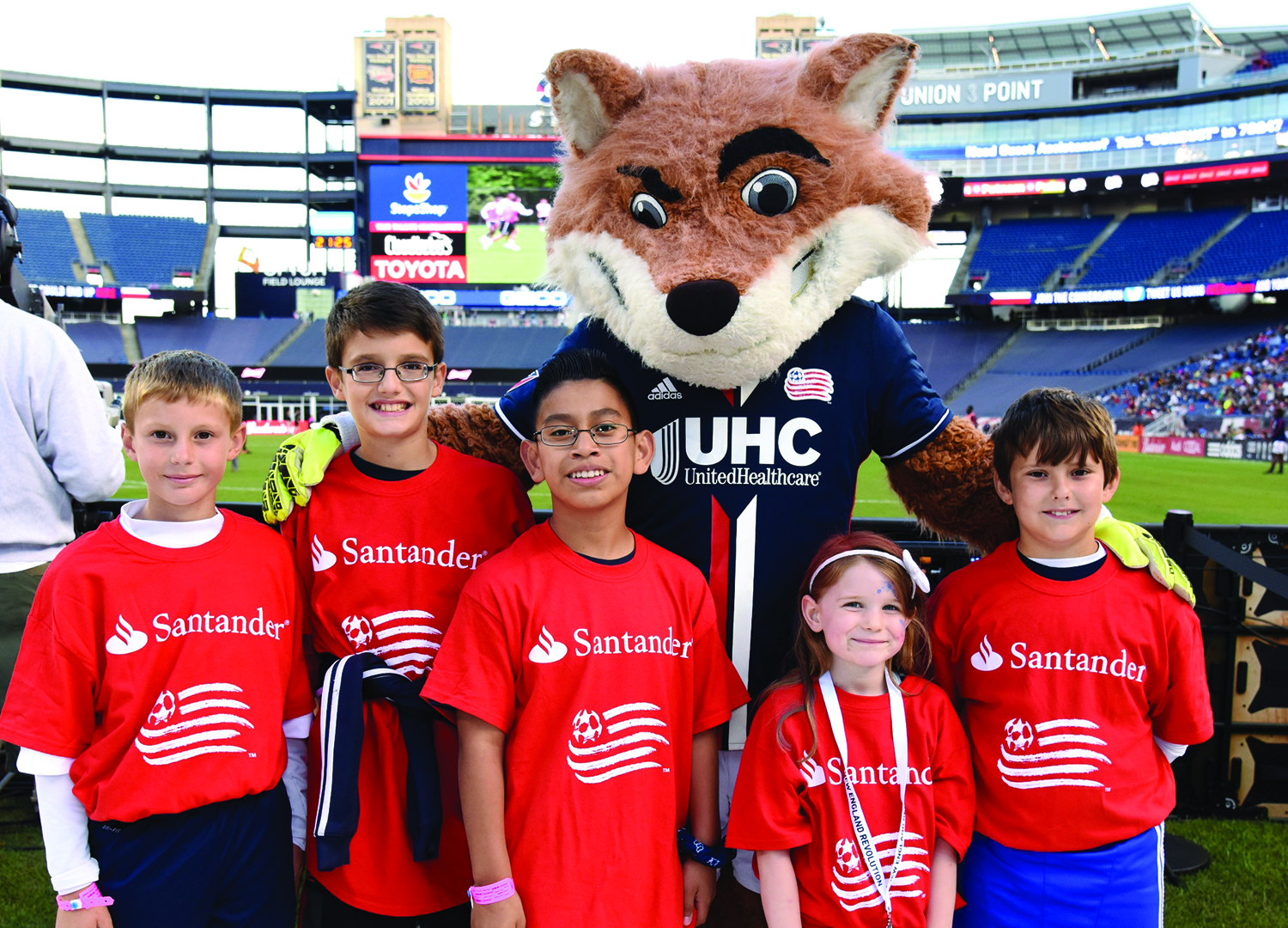 Franklin resident Michael Fernandez (second from the left) and fellow Santander Soccer Scholars posed for photo with New England Revolution mascot Slyde the Fox at Gillette Stadium prior to the New England Revolution match on July 29.