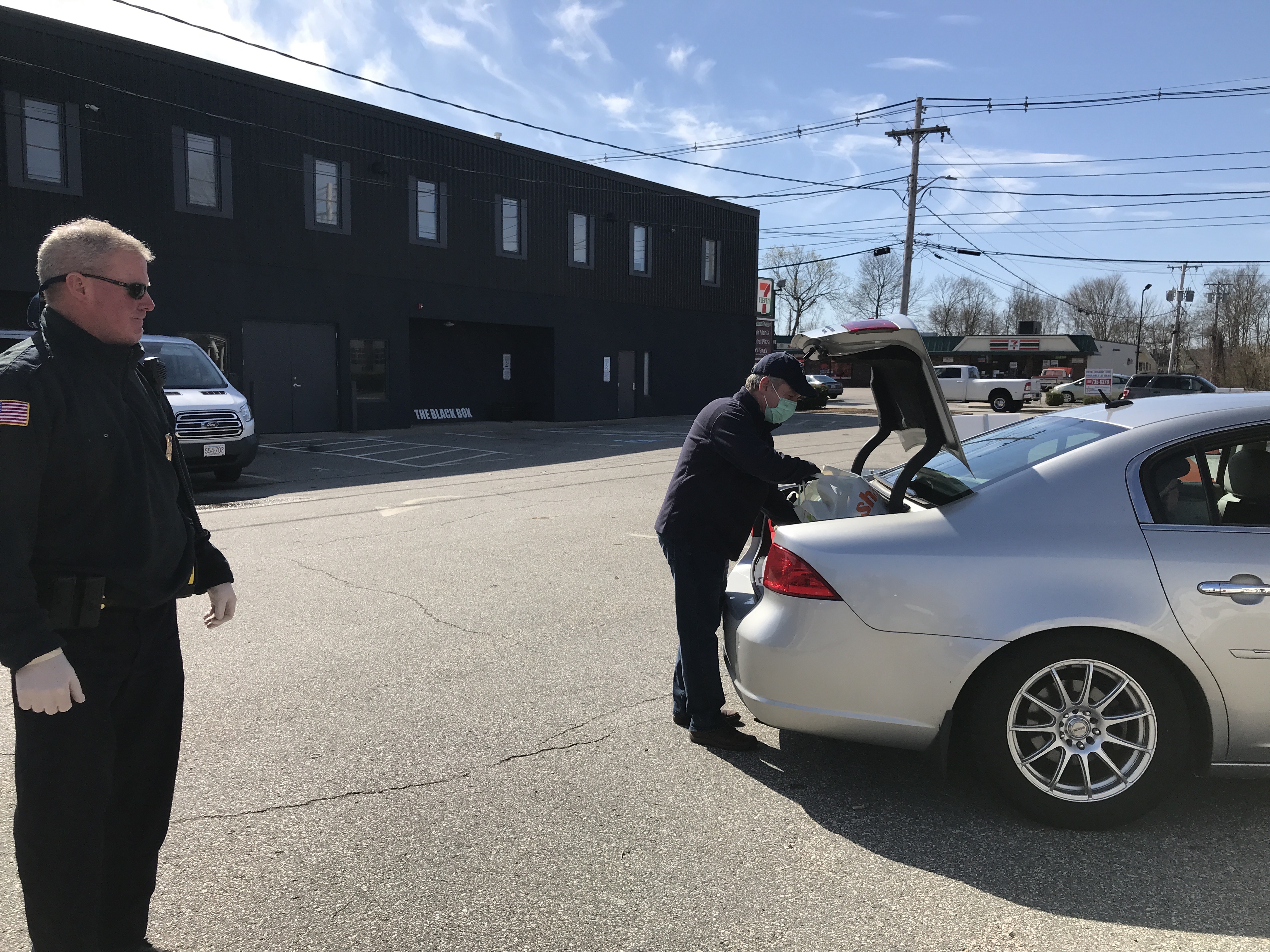 Franklin Food Pantry now has a drive-up model to minimize contact. Shown here, volunteer Jeff Roy helps pack a client’s trunk with pre-bagged food, with the help of Franklin Police.