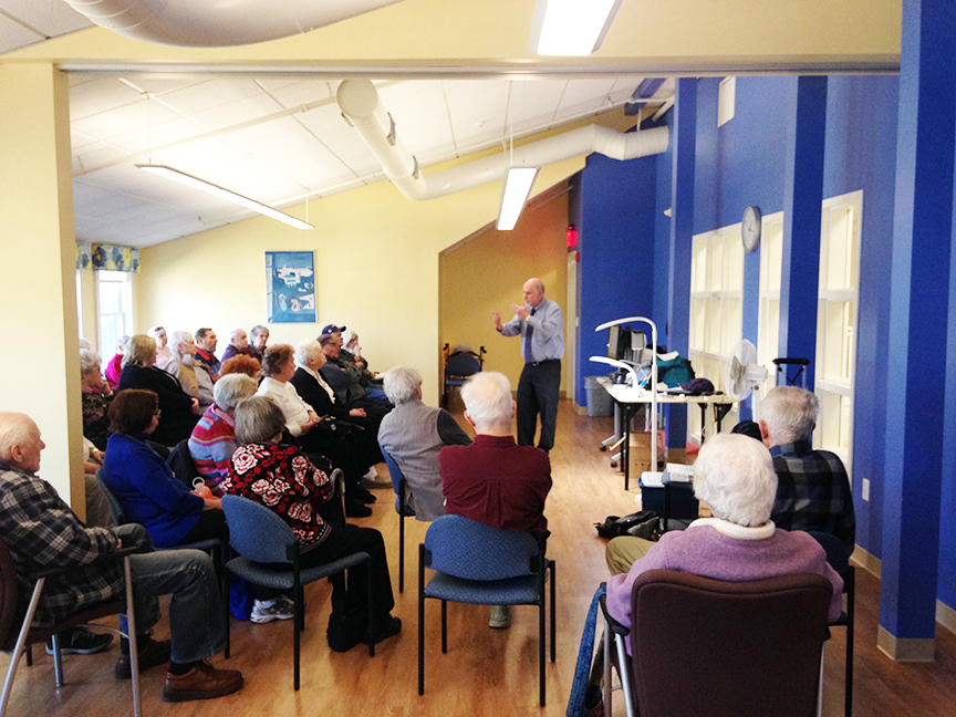 The Assistive Technology Center, or “Low Vision Center,” at the Franklin Senior Center is one of three centers in Massachusetts established by the Mass. Executive Office of Elder Affairs and Massachusetts Councils on Aging. It demonstrates assistive technology to those experiencing vision loss, and offers a drop-in program on the second Tuesday of each month. Here, Stu Flom from Adapti-Vision demonstrates an optical reader called an OCR to a group of about 35 attendees.