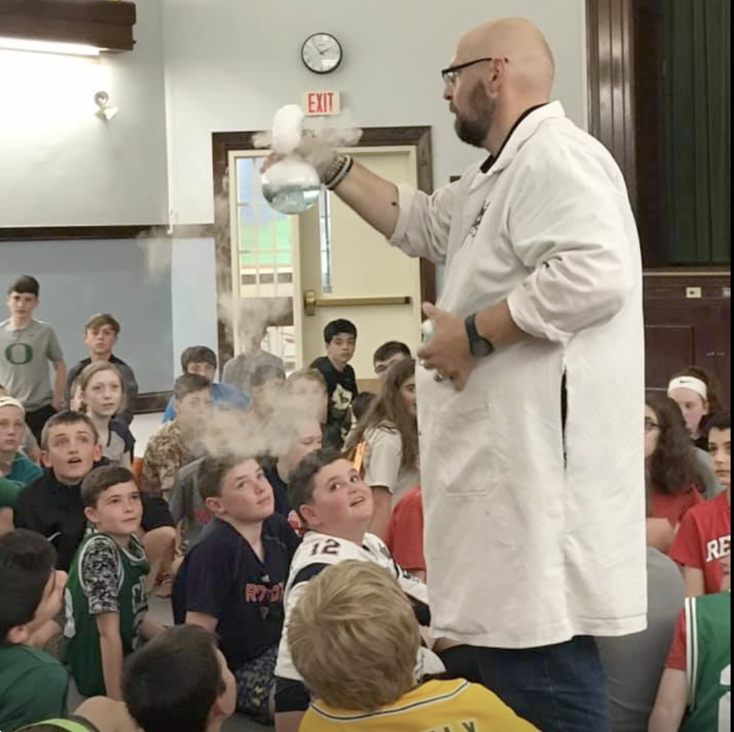 The WHY of science was explained to sixth graders during a visit by a Mad Scientist, who taught how to make a human electrical circuit, create a tornado in a tube, fabricate a tiny lightning storm, and “catch” a shadow.