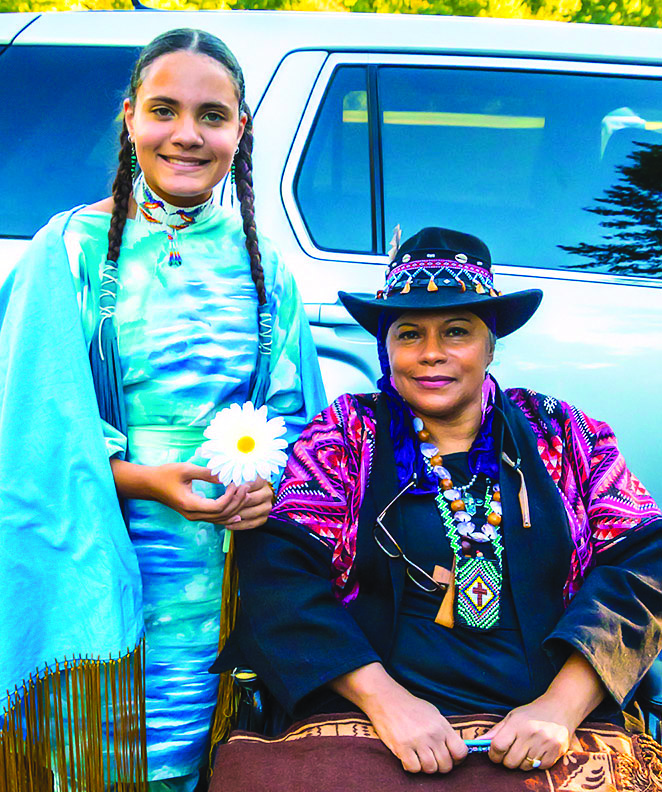 Chief Caring Hands (right) next to Keteri Tekawitha (left), who holds a daisy in honor of Rita “Daisy” Orcut of Natick’s own “Sizzling Seniors.” (Photo/Roger Gordy)